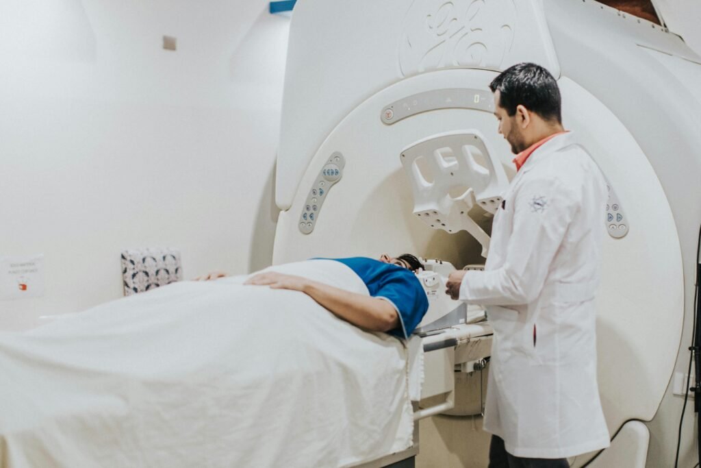 Doctor assisting patient in MRI scanner during medical examination in hospital setting.