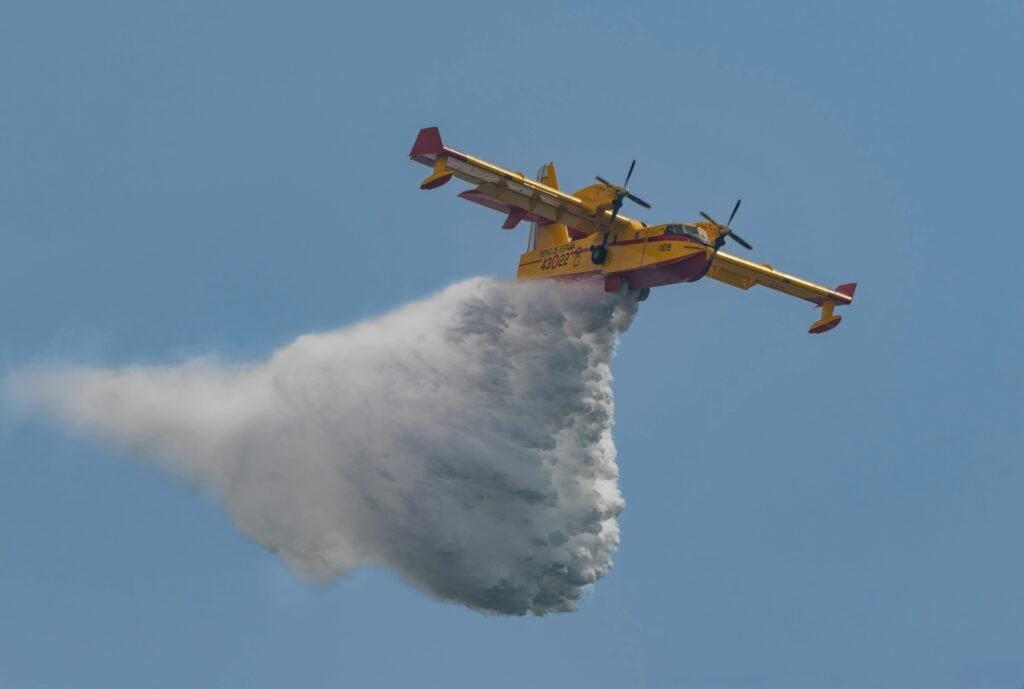 Aerial view of a firefighting plane deploying water over a fire in an emergency response.